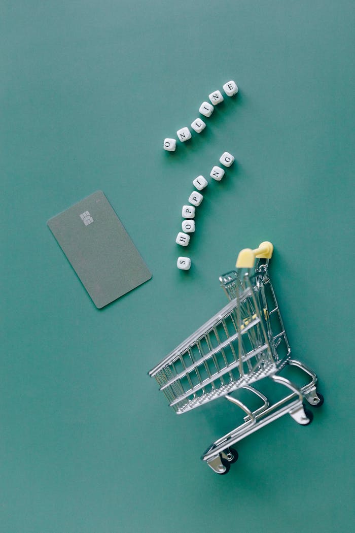 A conceptual image featuring a mini shopping cart, credit card, and letter blocks spelling 'online shopping' on a green background.